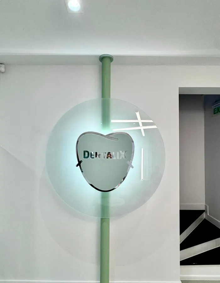 Sigla Dentalix iluminată, montată pe coloana verde de lângă scară, în clinica din Băicoi