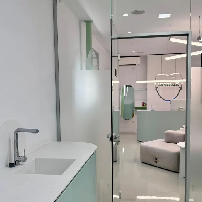 Chiuvetă și mobilier verde mint la Dentalix Băicoi, cu recepția văzută prin ușa de sticlă