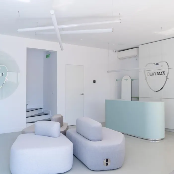 Canapele deschise la culoare și biroul de recepție din clinica Dentalix Băicoi
